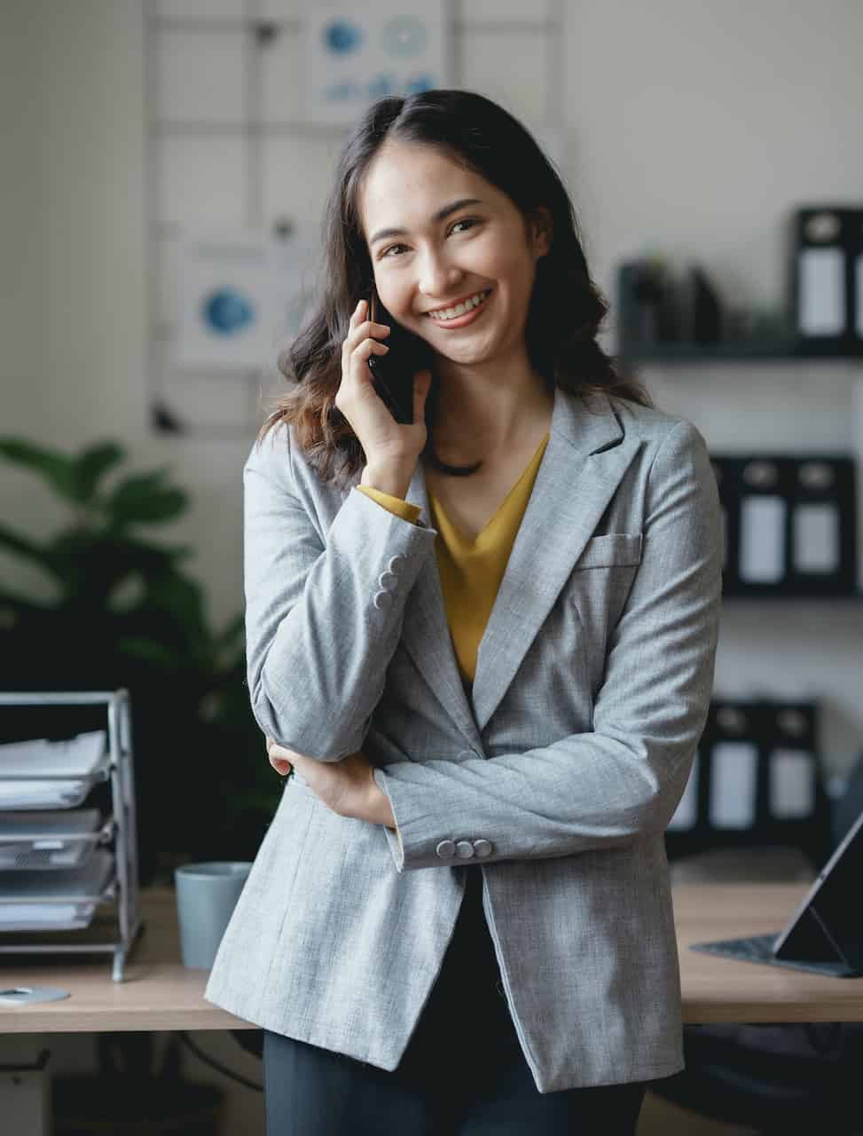 Asian businesswoman, real estate agent, talking on the phone with a customer about the details of selling a house How to buy a house step by step in the office and use the tablet.