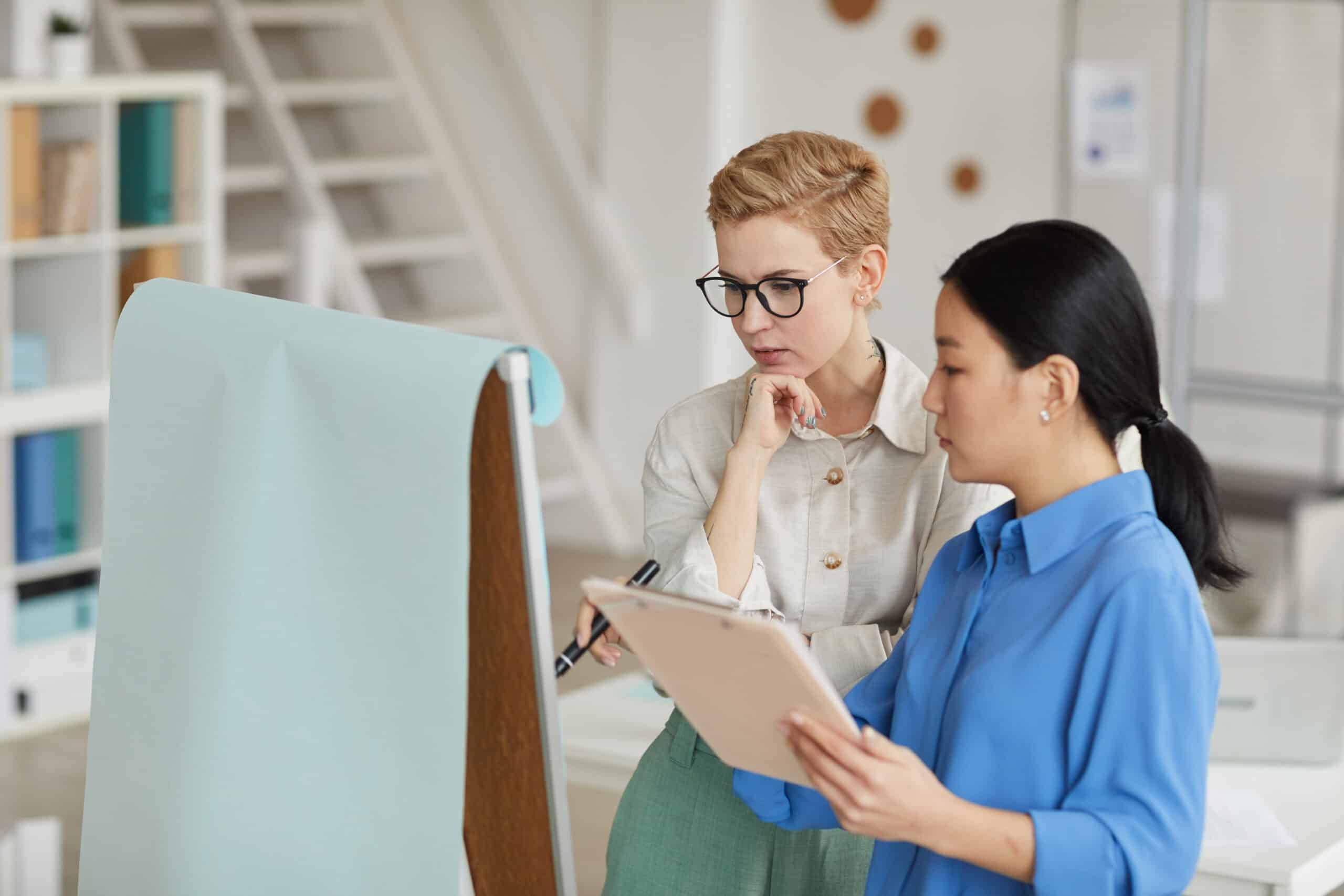 Businesswomen Writing on Board in Office